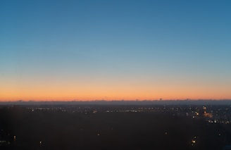 Evening view of solar panels with city lights beginning to twinkle in the background.