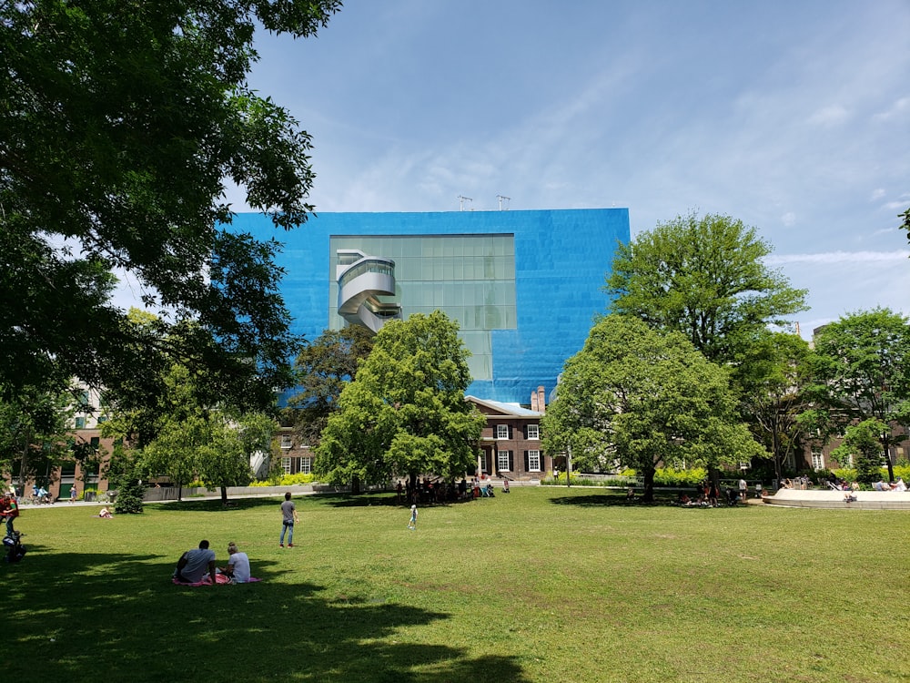 people walking on green grass field near building during daytime