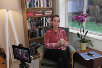 A thoughtful adult reading a digital tablet surrounded by books and tech gadgets in a cozy study.
