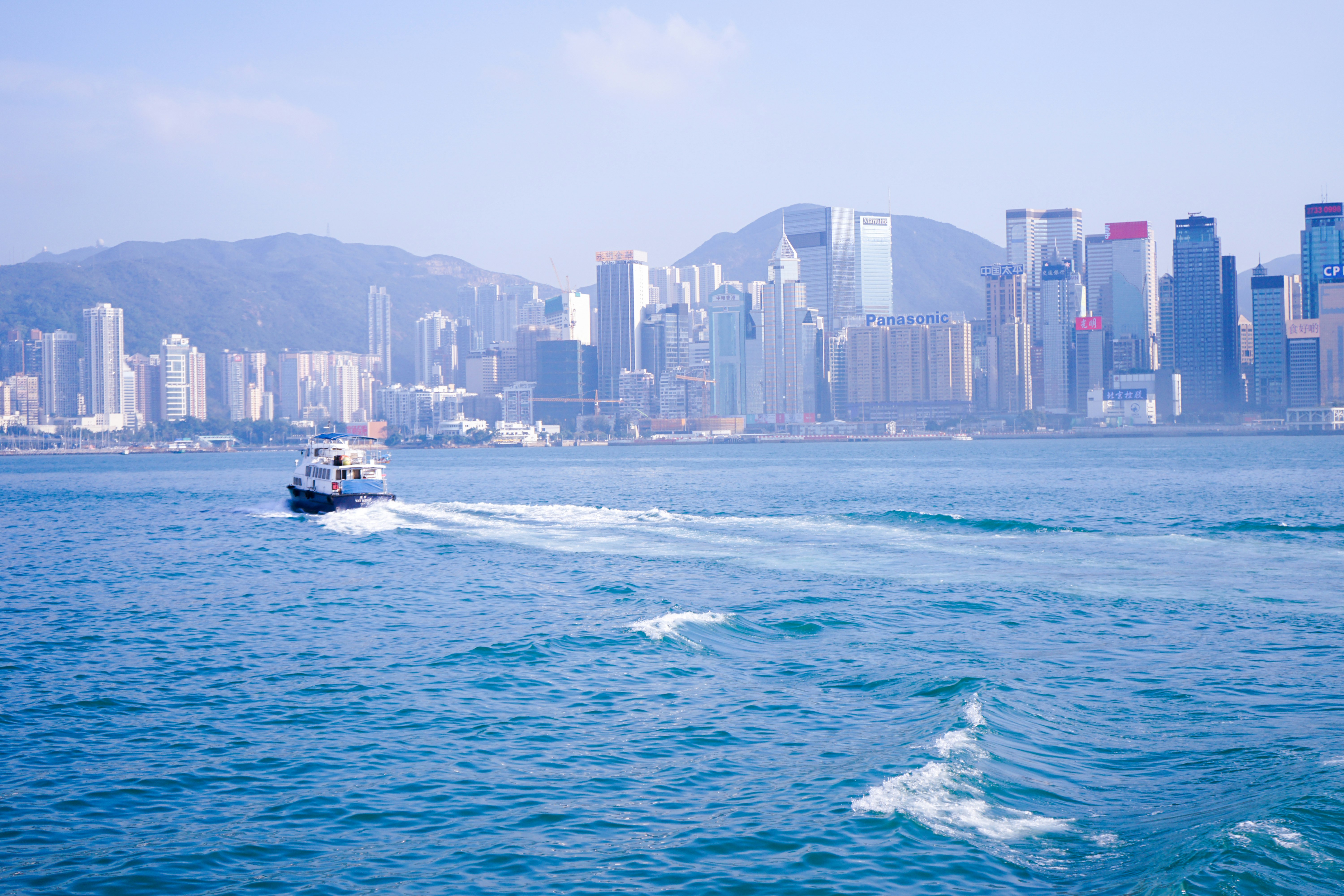 white and black boat on sea near city buildings during daytime