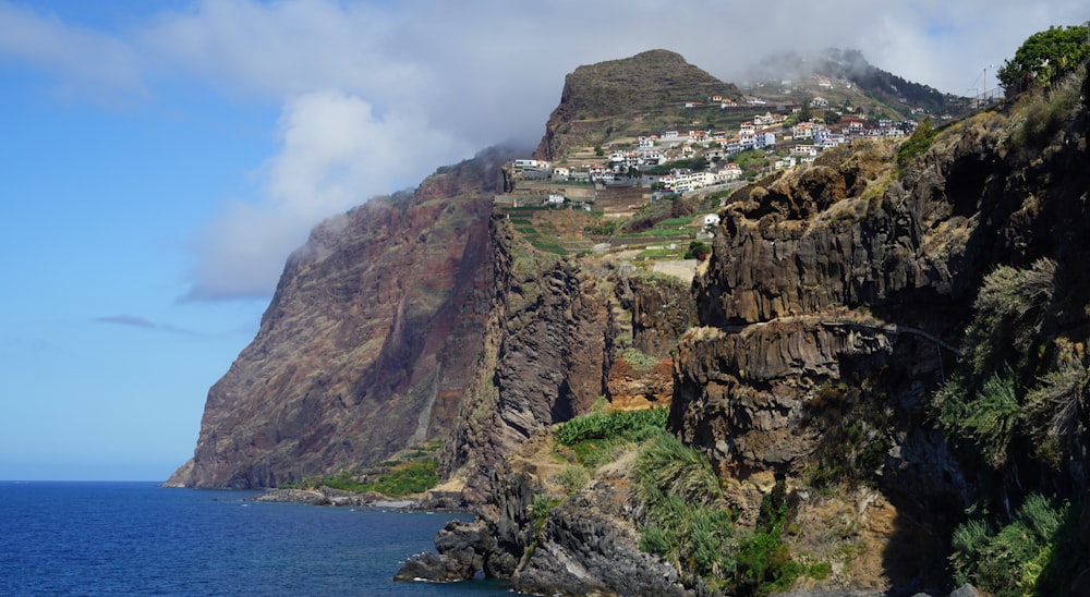 brown and green mountain beside body of water under white clouds and blue sky during daytime