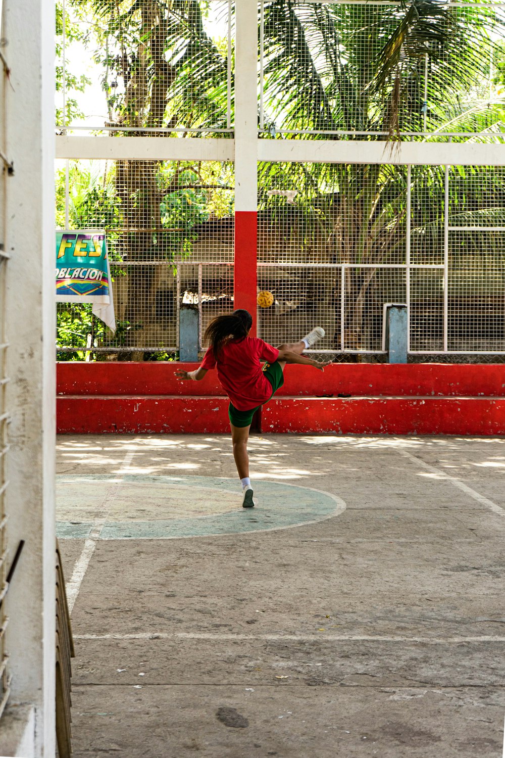 빨간 셔츠와 검은 반바지를 입은 남자가 낮에 농구를 하고 있다