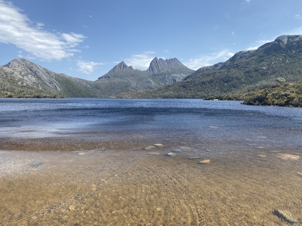 body of water near mountain under blue sky during daytime