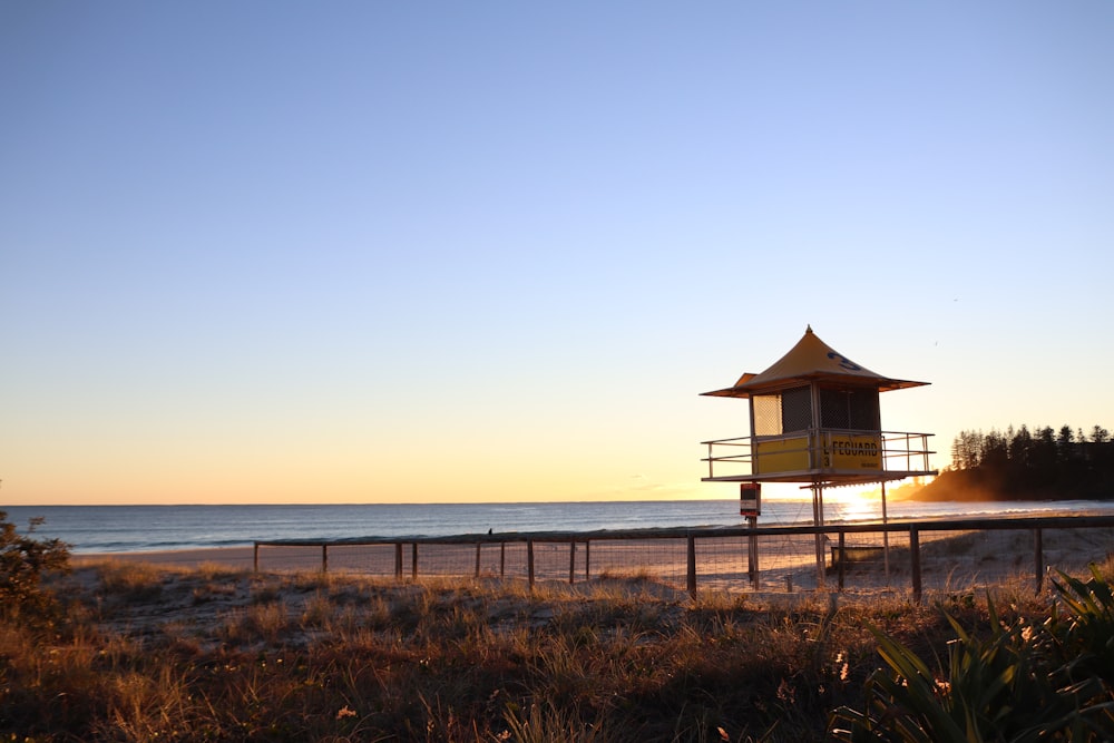 brown wooden house on brown field near sea during daytime