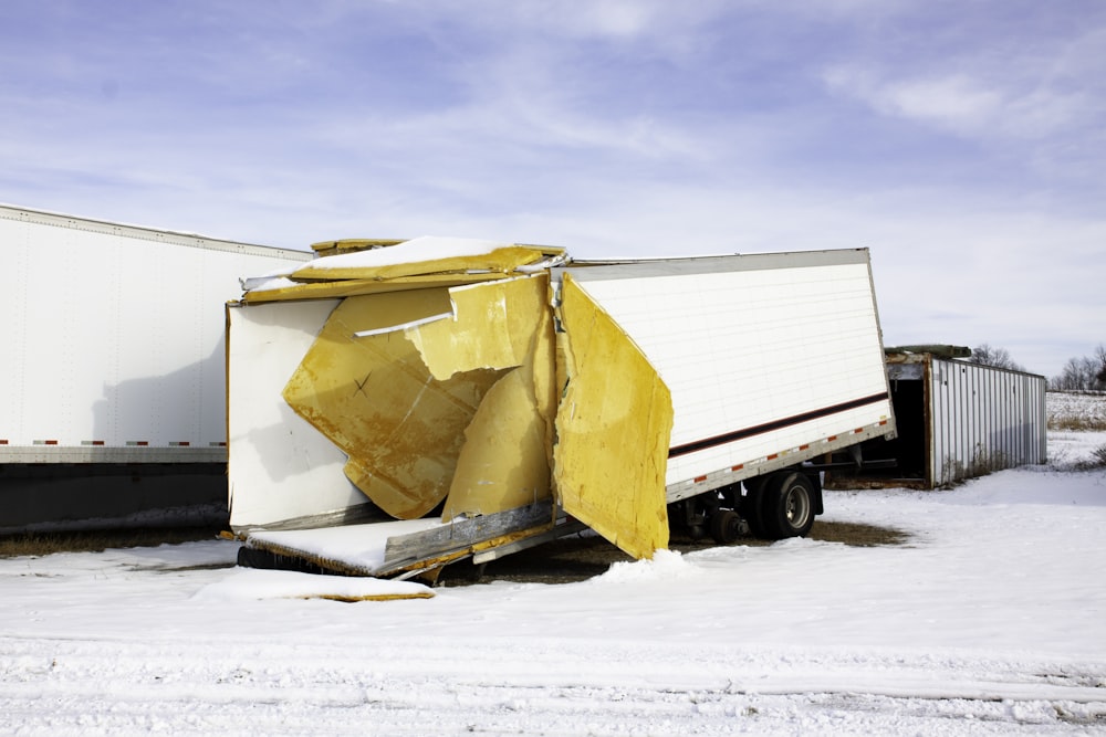 caminhão amarelo e branco no chão coberto de neve durante o dia