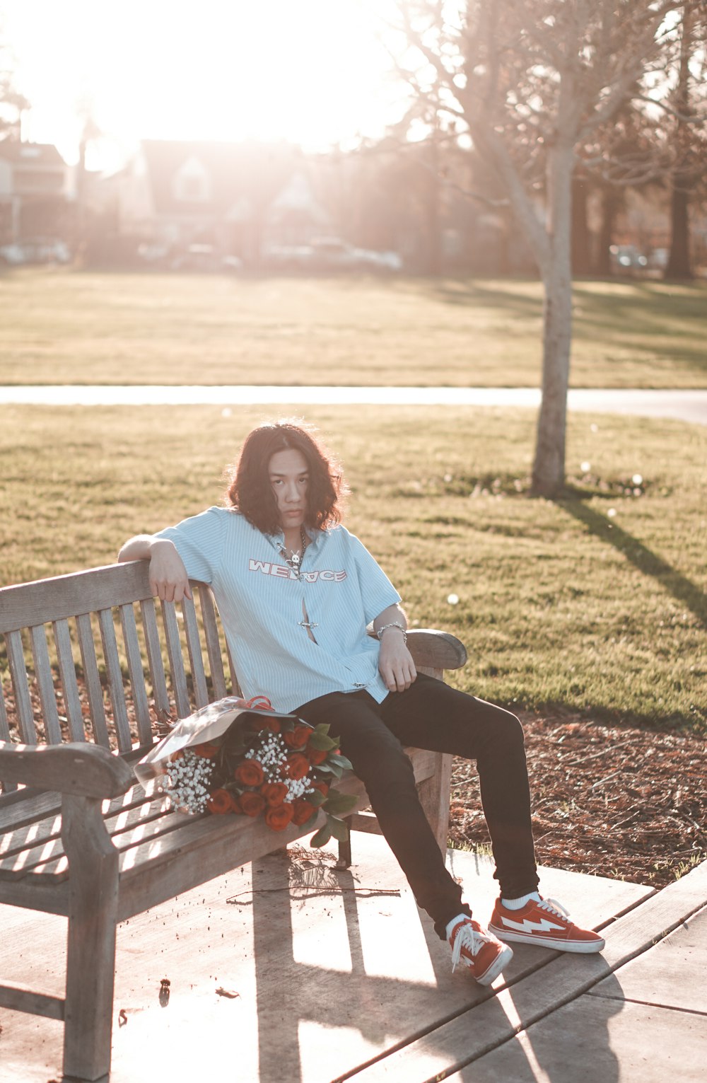 woman in white long sleeve shirt sitting on brown wooden bench during daytime