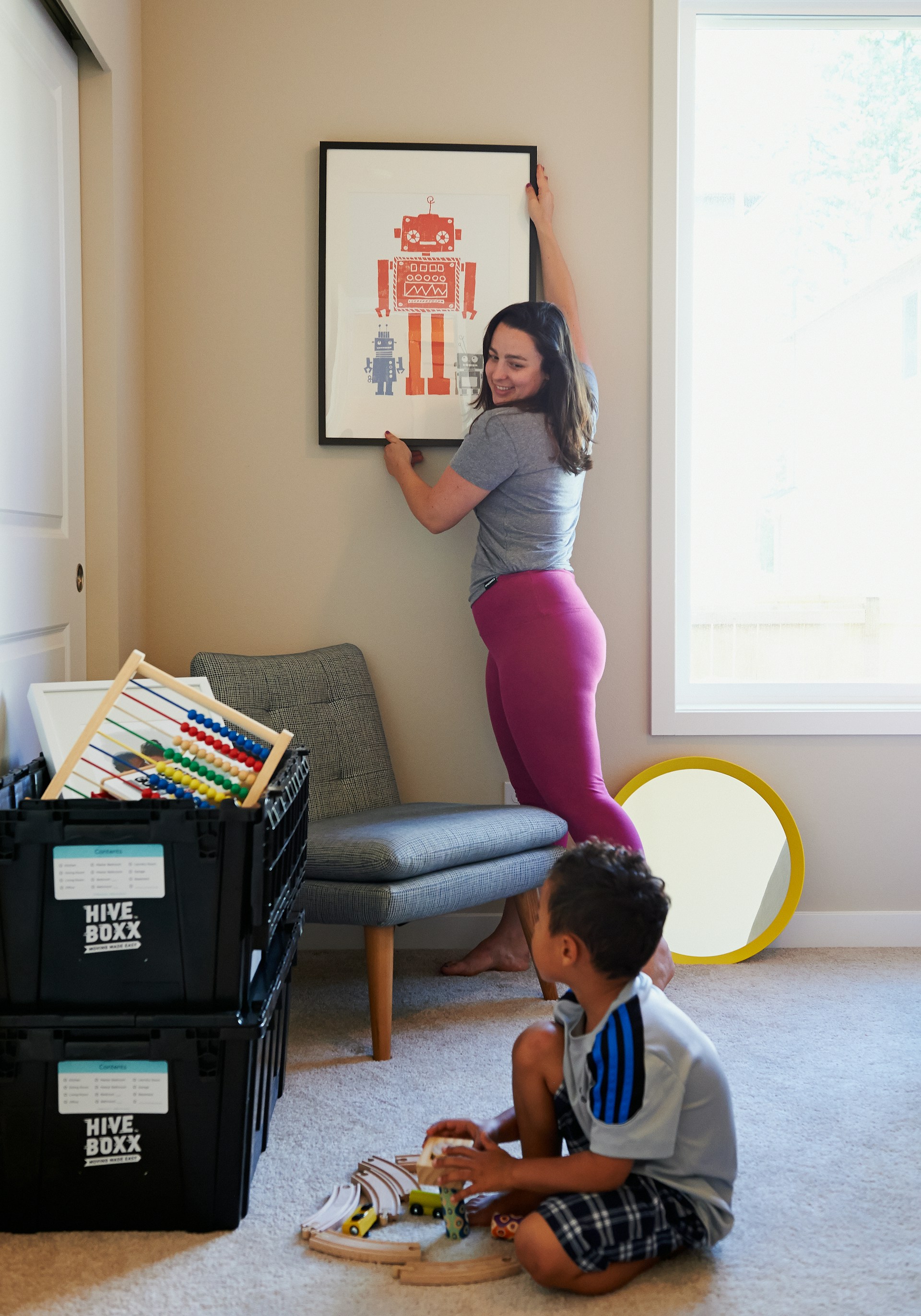 woman in gray shirt and pink pants sitting on gray chair