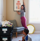 woman in gray shirt and pink pants sitting on gray chair