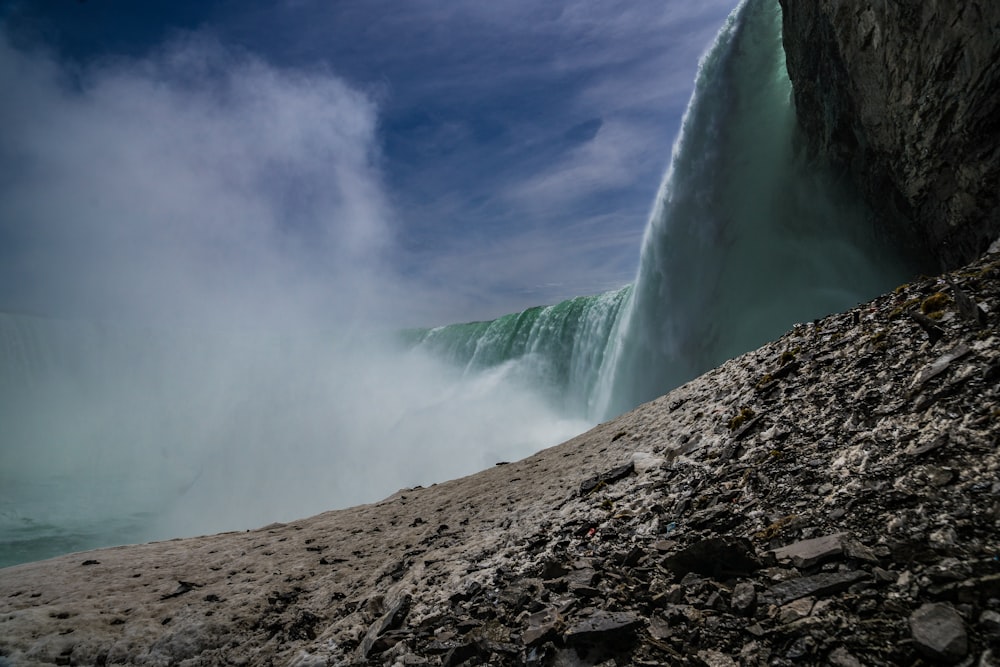 waterfalls under white clouds and blue sky during daytime