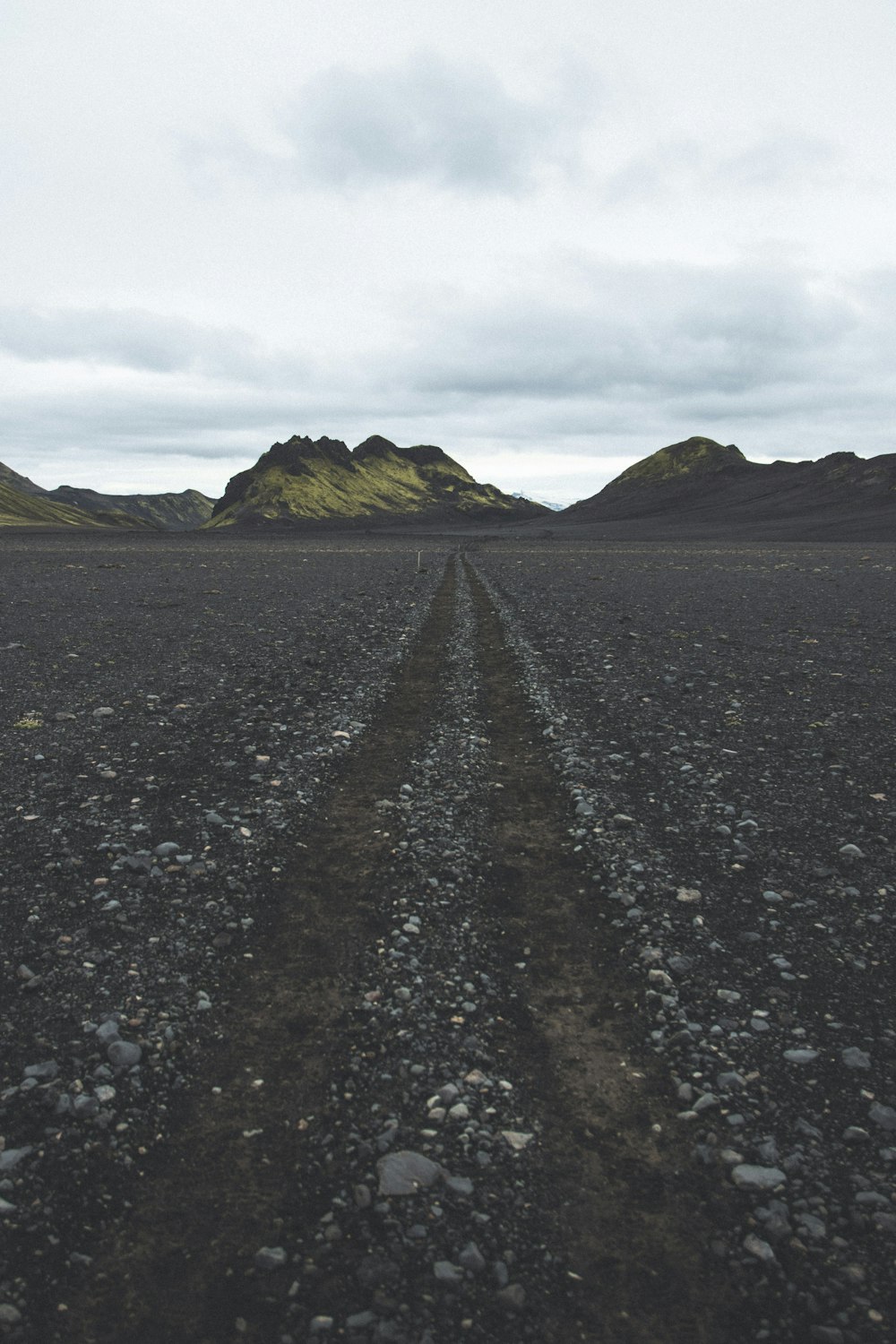 gray road between green grass field during daytime