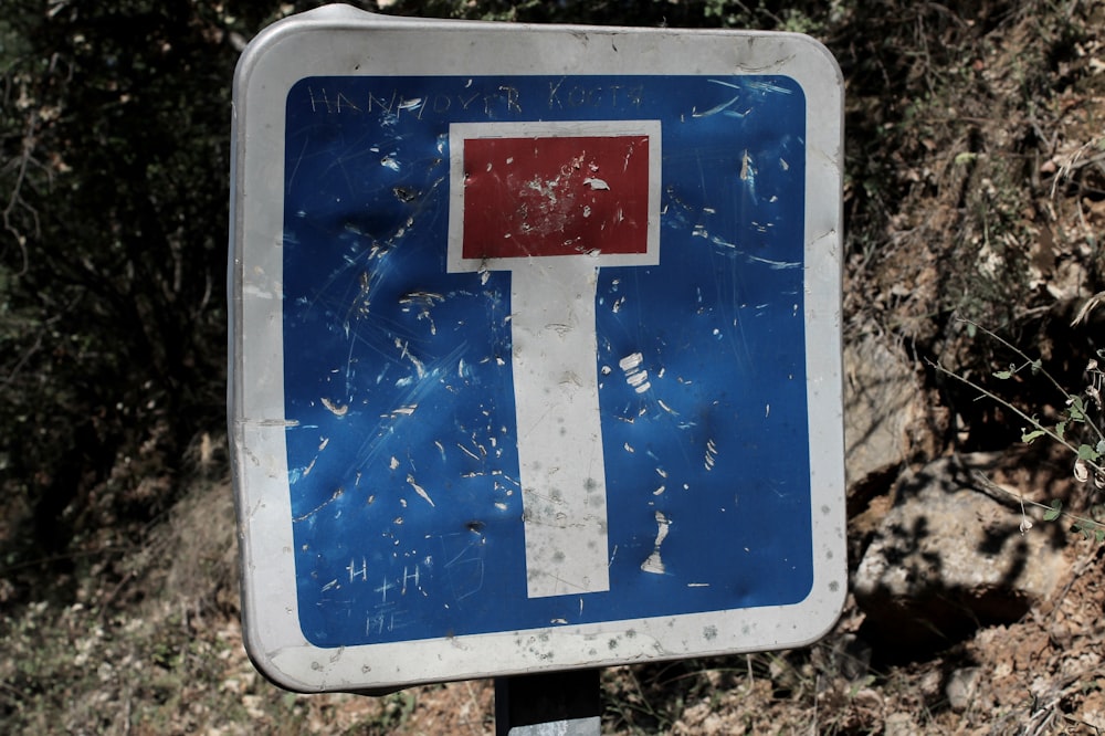 Un letrero azul y blanco sentado al costado de una carretera