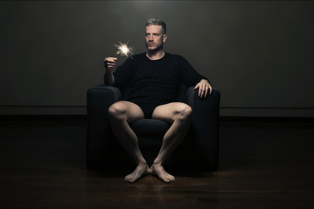 man in black tank top sitting on black leather armchair