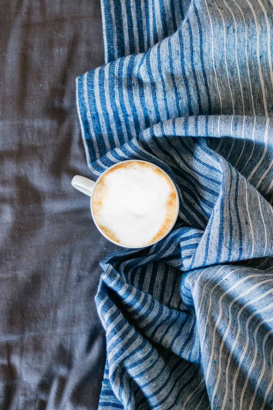 white ceramic mug on gray textile