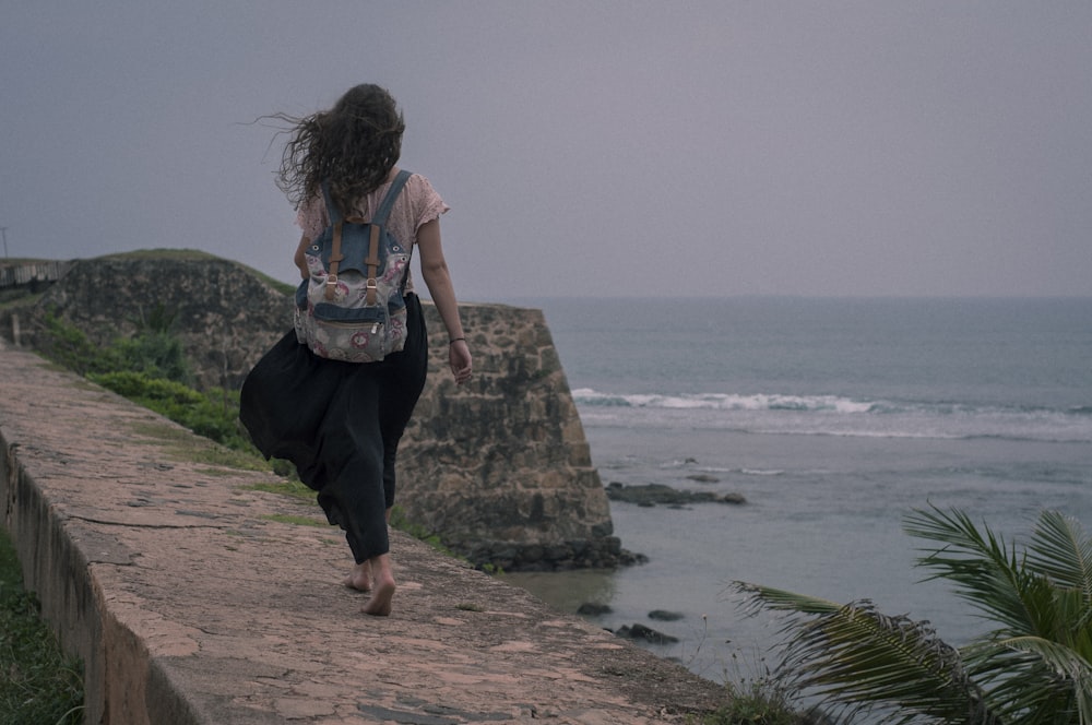 woman in blue and black tank top and black pants standing on brown rock formation near near near near near