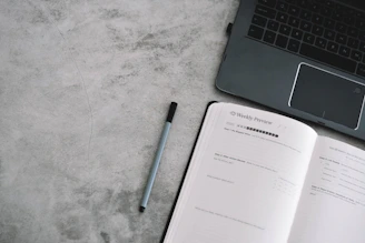 An open calendar with a pen and a laptop showing a booking page.