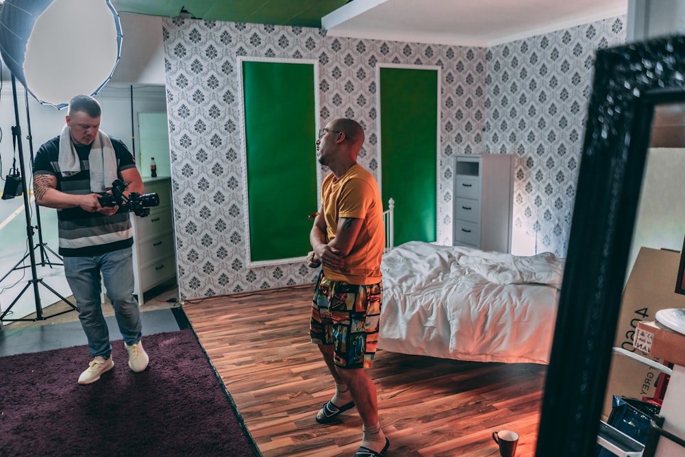 man in yellow and white crew neck t-shirt standing beside bed