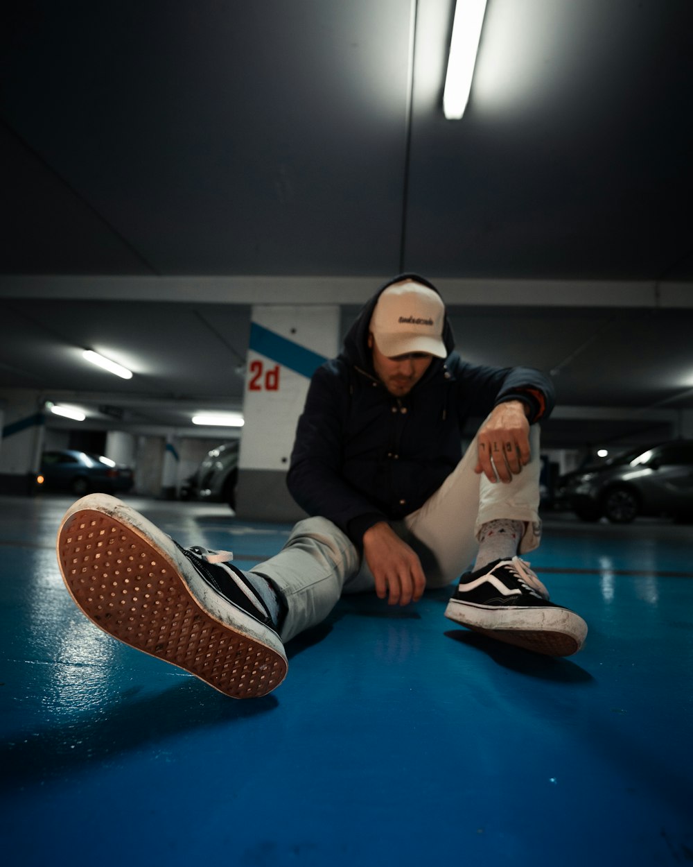 woman in black jacket and white pants sitting on blue floor