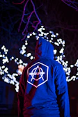 person in blue and red hoodie standing in front of white string lights
