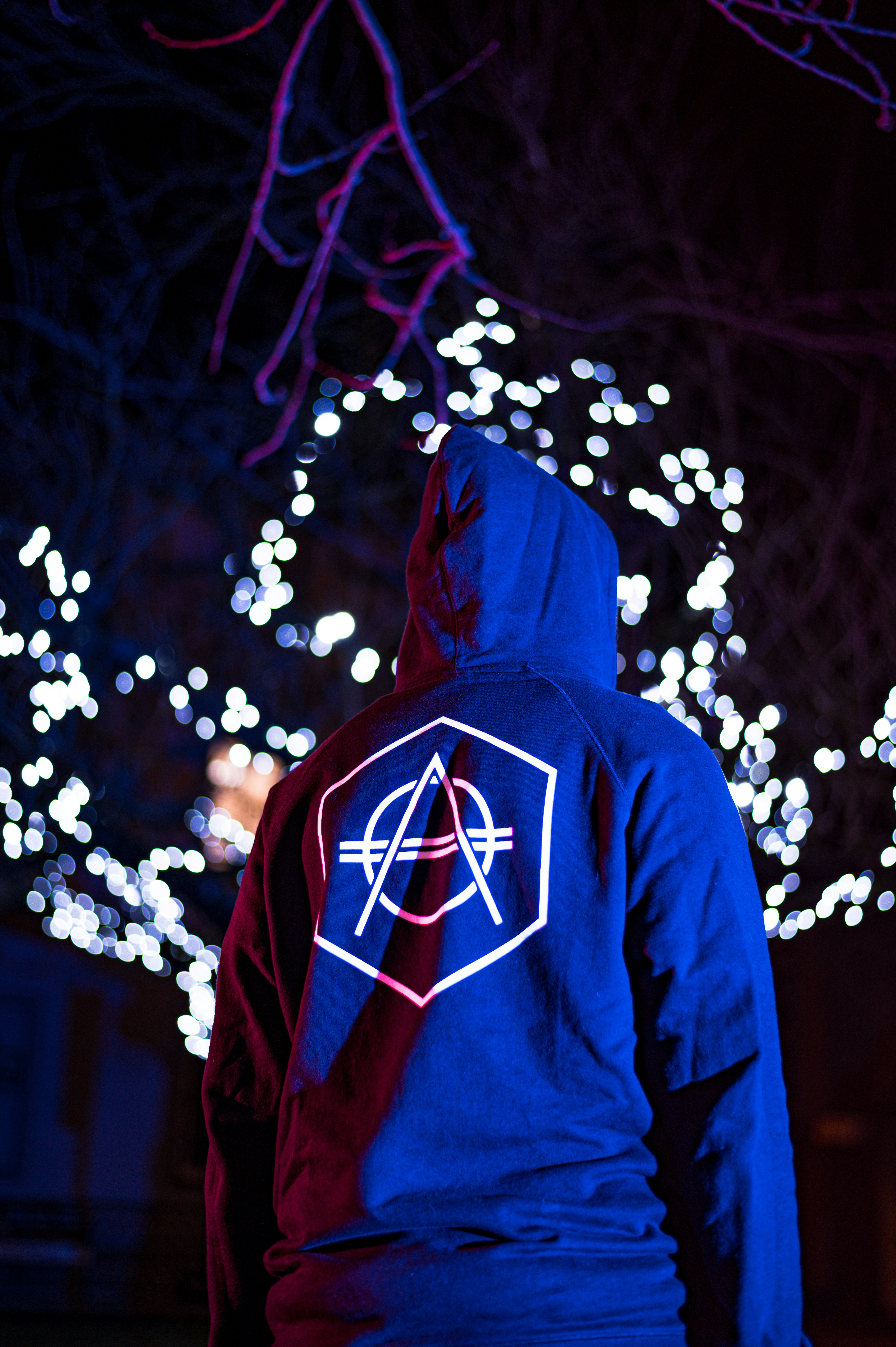 person in blue and red hoodie standing in front of white string lights