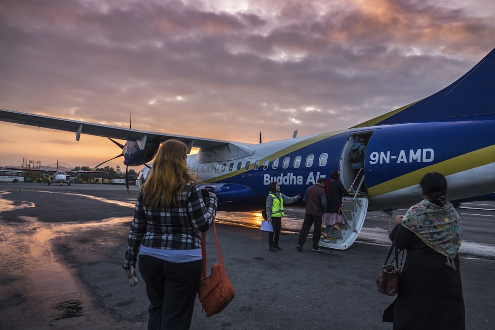 woman in blue denim jacket standing near blue and white airplane during daytime