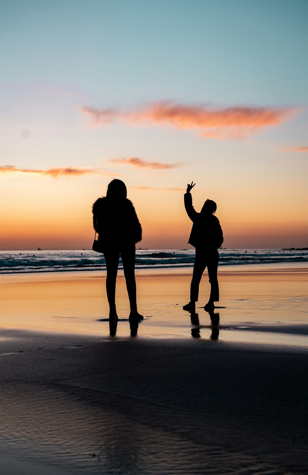 silhouette of 2 person standing on beach during sunset