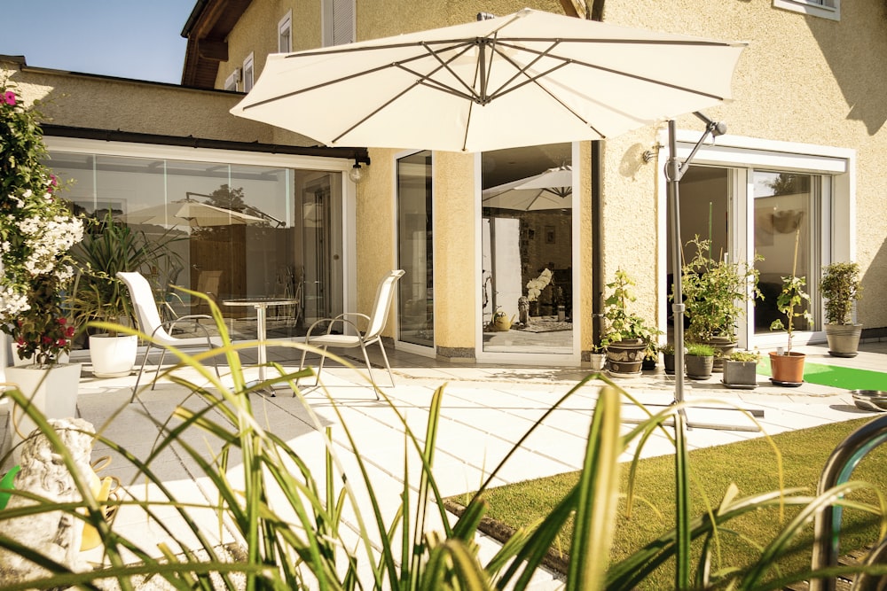 white patio umbrella near green plants during daytime