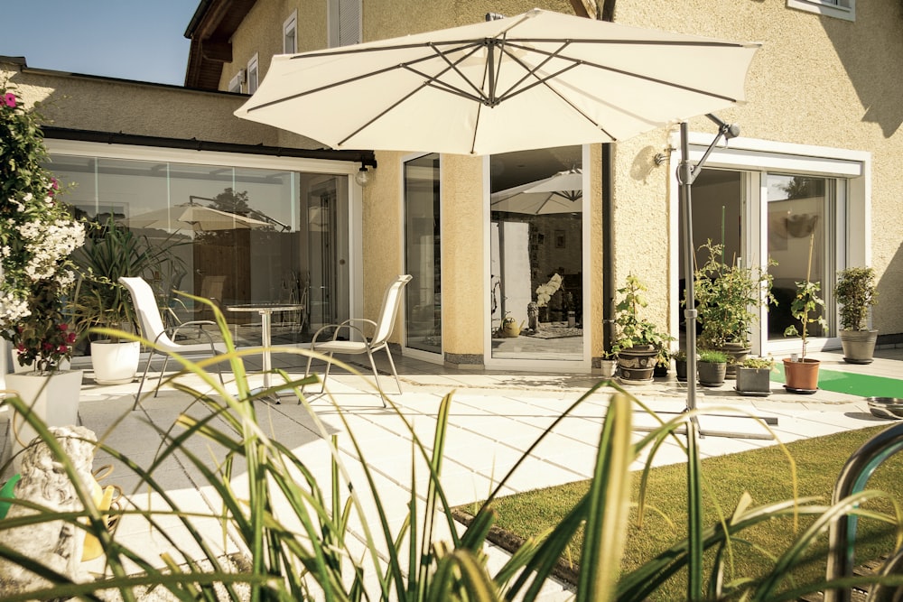 white patio umbrella near green plants during daytime