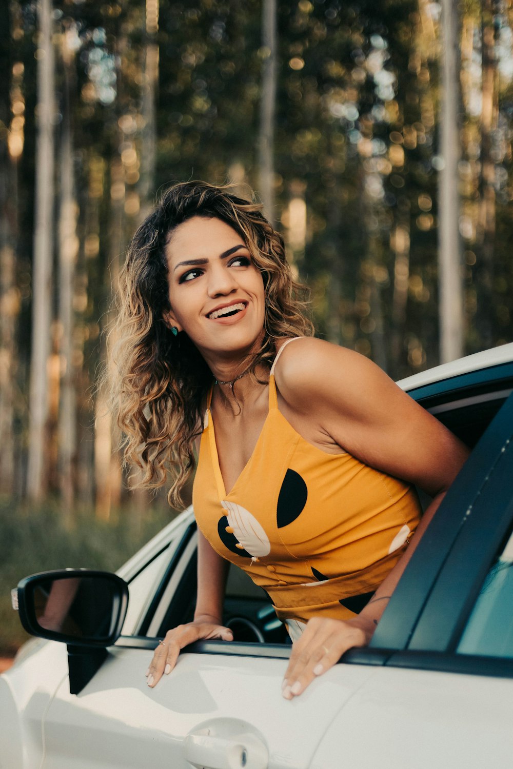 woman in orange tank top sitting on car