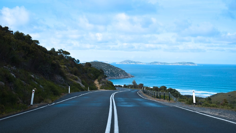 gray concrete road near body of water during daytime