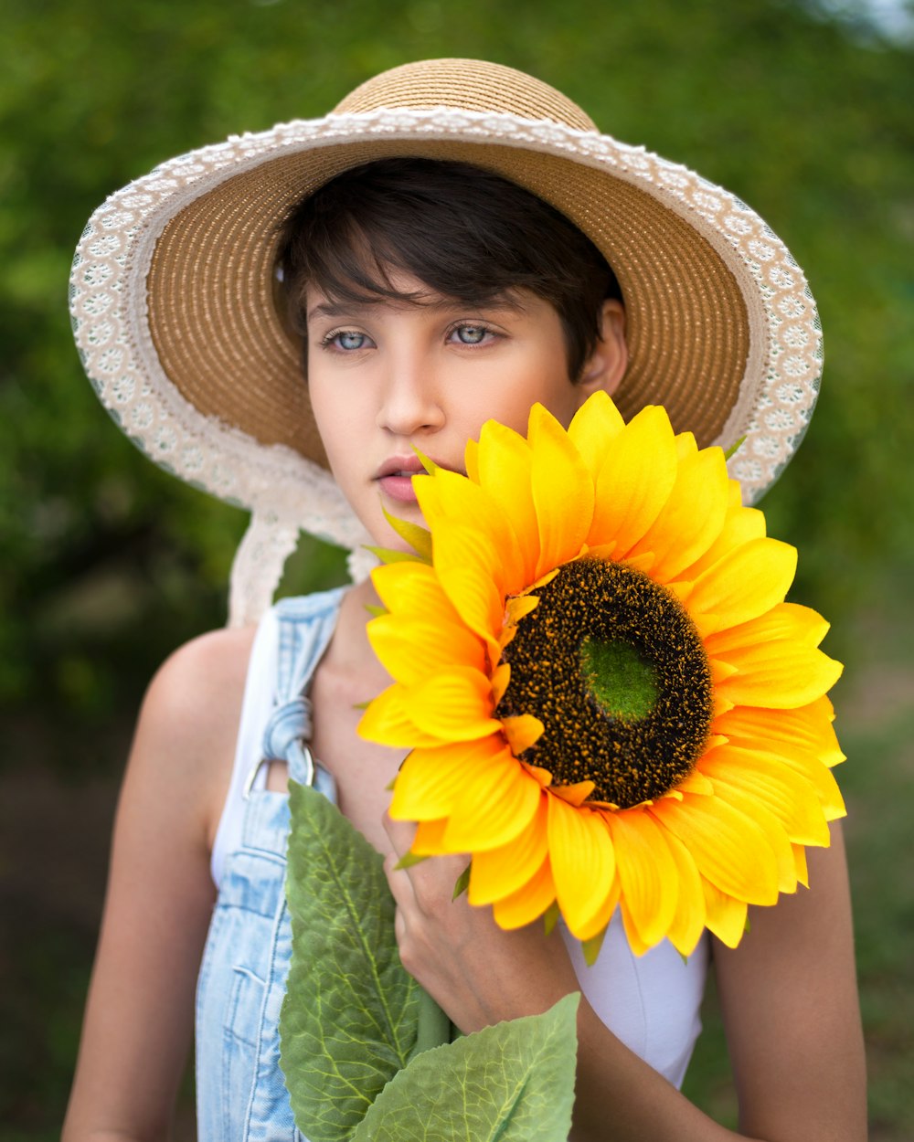 girl in yellow sun hat holding sunflower