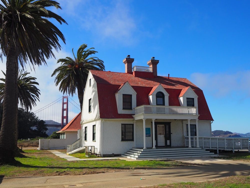 white and red concrete house near palm tree under blue sky during daytime