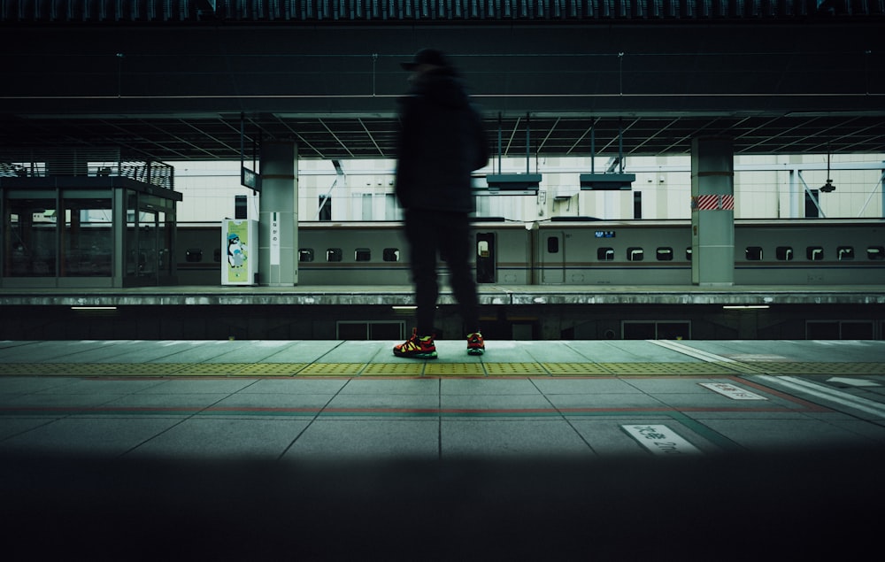 man in black jacket walking on train station