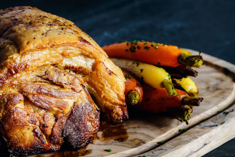 Roasted pork and vegetables resting on a wooden board, ready to serve