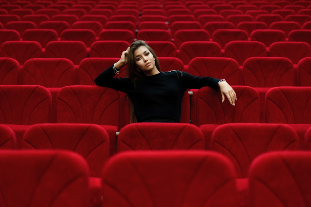 mulher na camisa preta de manga comprida sentada na cadeira vermelha