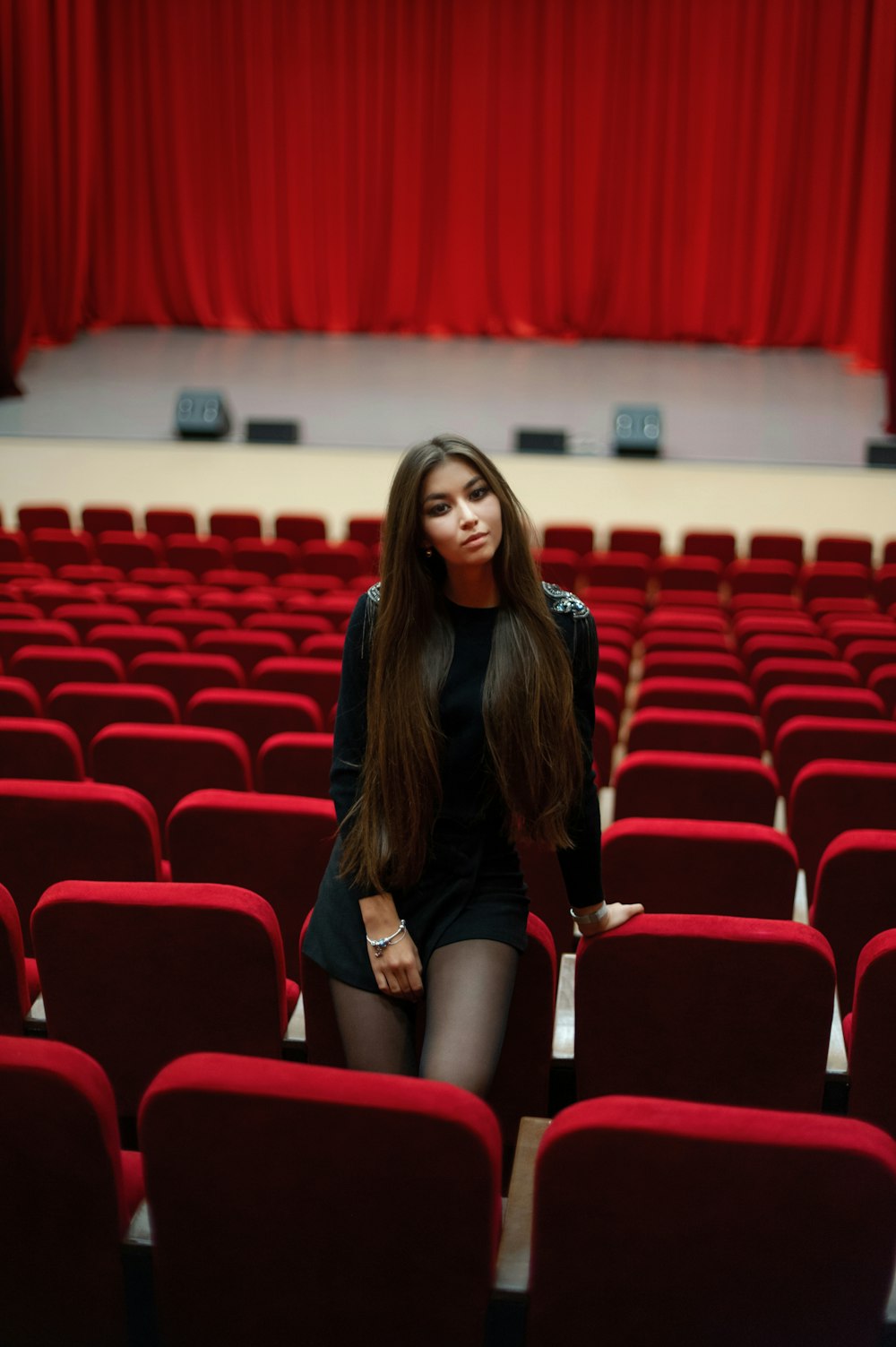 woman in black shirt and black shorts sitting on red chair