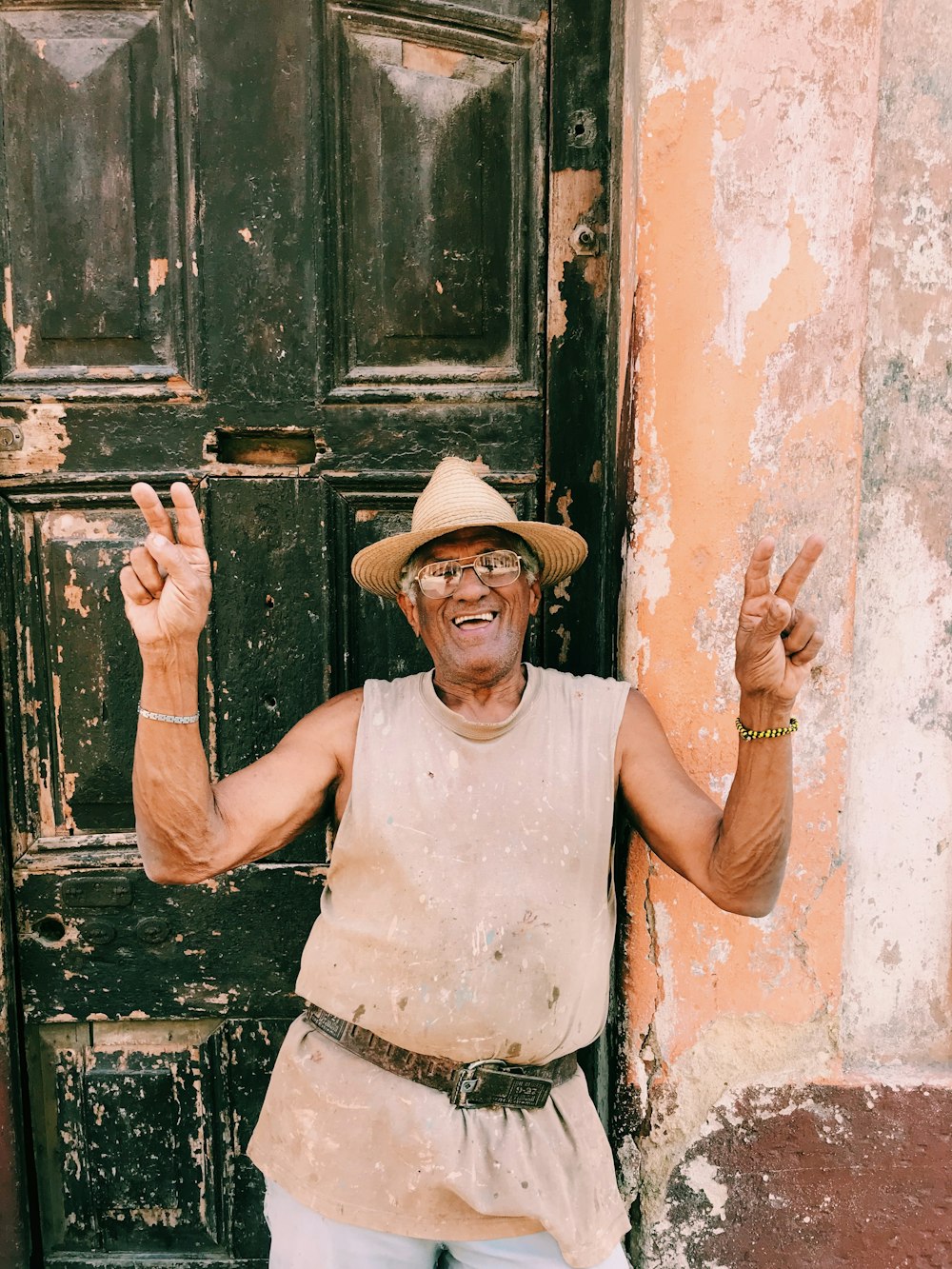 man in white tank top and brown cowboy hat leaning on brown wooden door