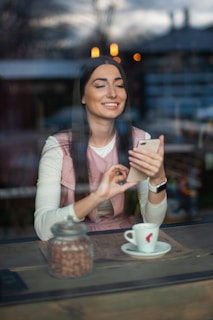 A smiling Korean woman enjoying coffee while browsing Finhan on her tablet in a bright, modern café.