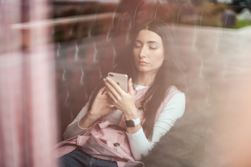 woman in white long sleeve shirt holding gold iphone 6