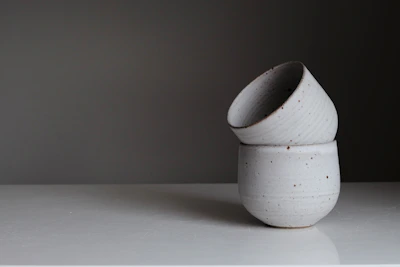 A stack of three cute, minimalist mugs in soft neutral tones against a light background.