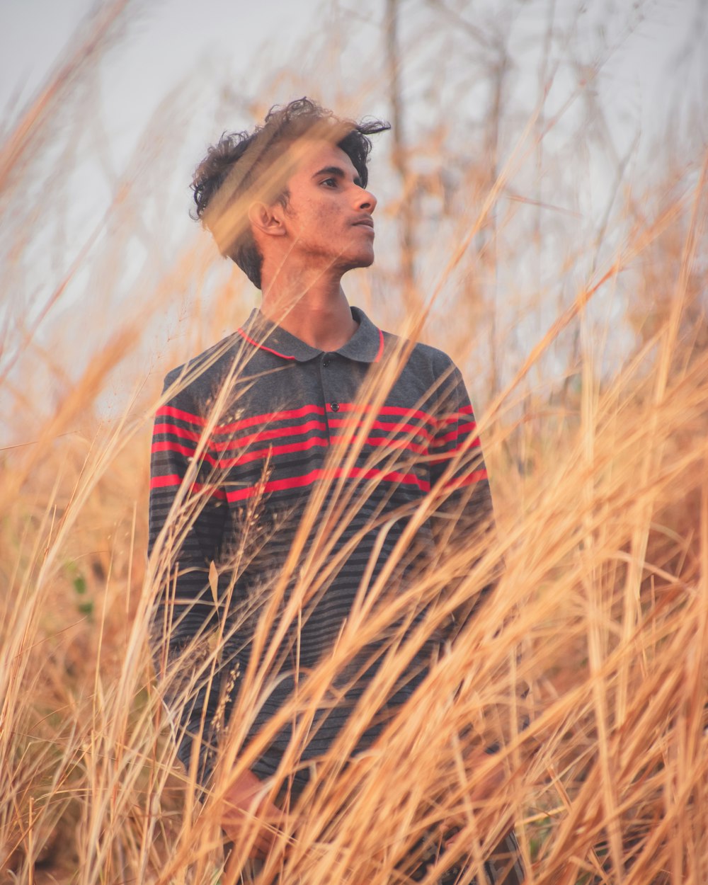 man in black and red crew neck shirt standing on brown grass field during daytime