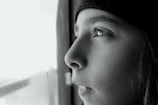 A close-up of a person gazing thoughtfully out a window.