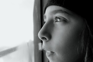 A close-up of a thoughtful person looking out a window.