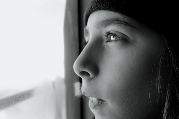 A close-up of a thoughtful person looking out a window.