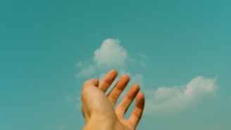 persons left hand under blue sky and white clouds