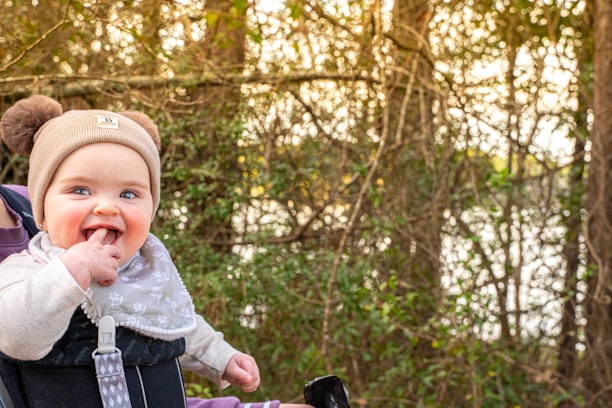 A baby wearing soft, nature-inspired clothing in a Galician forest setting.