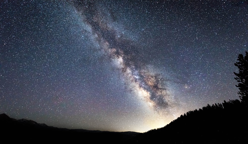 silhouette of mountain under blue sky with white clouds during night time