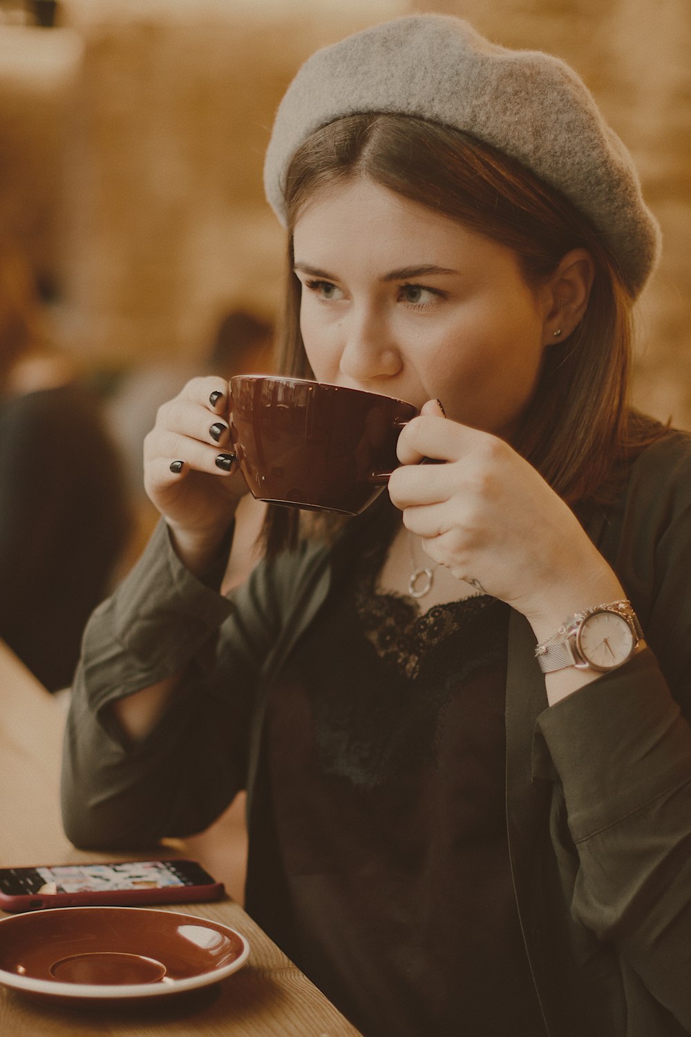 woman in black long sleeve shirt holding brown ceramic mug