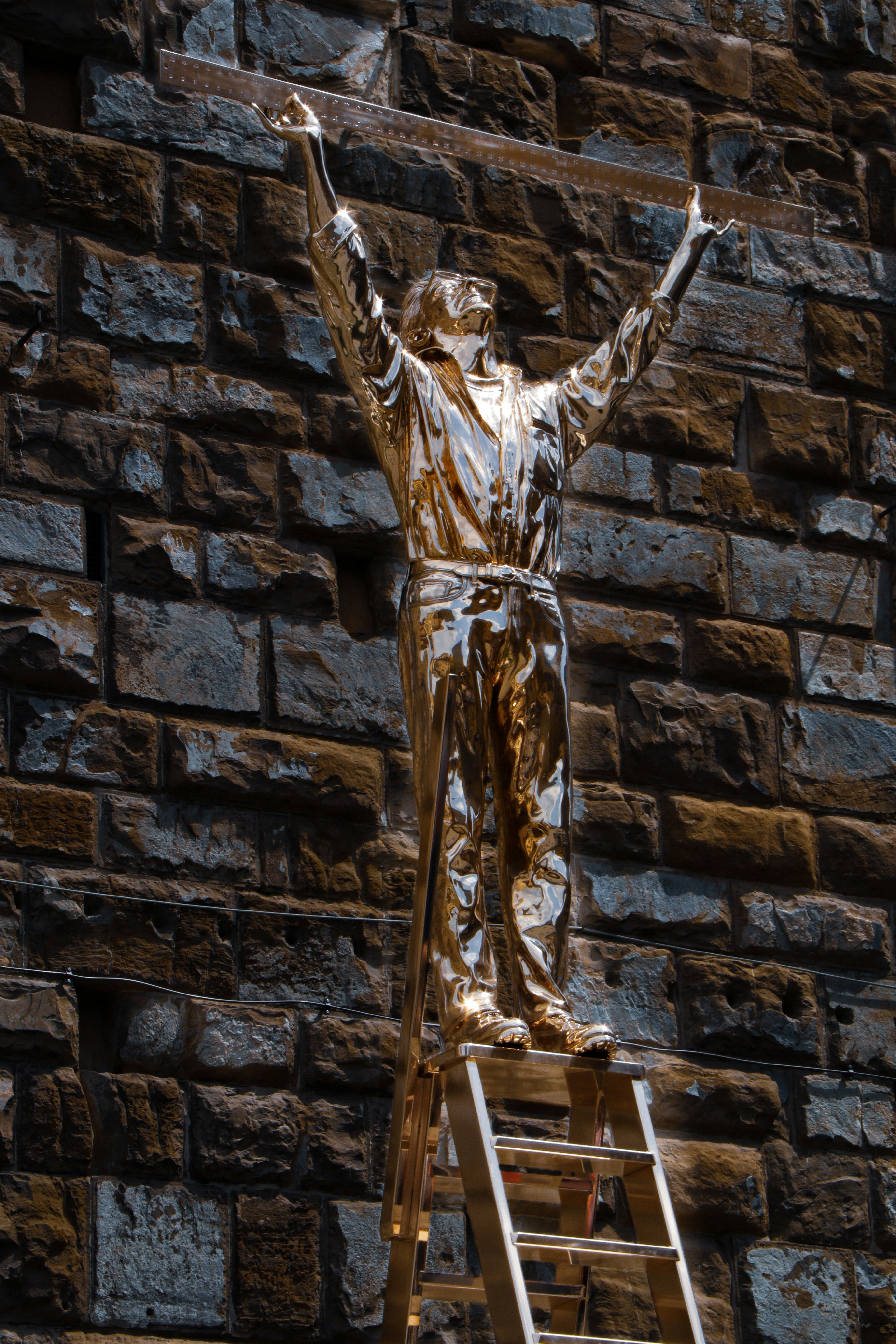 gold statue of man on black brick wall