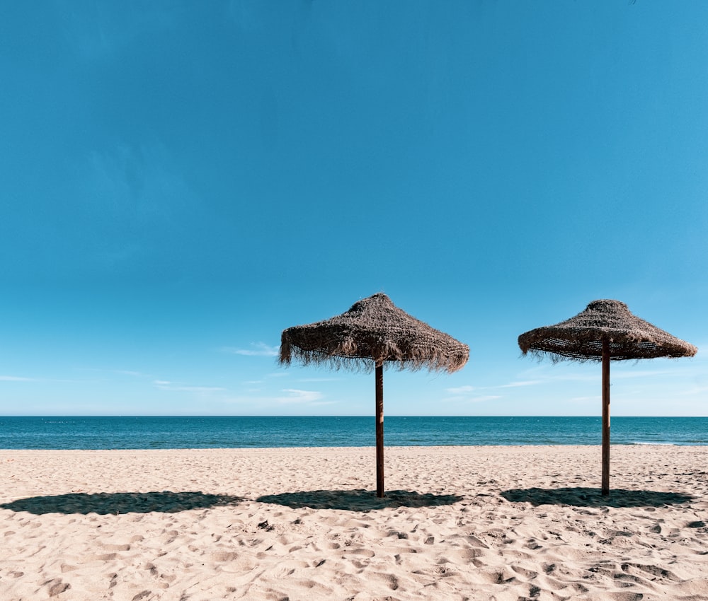 brown beach umbrellas on beach during daytime