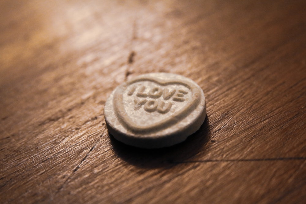 silver round coin on brown wooden table